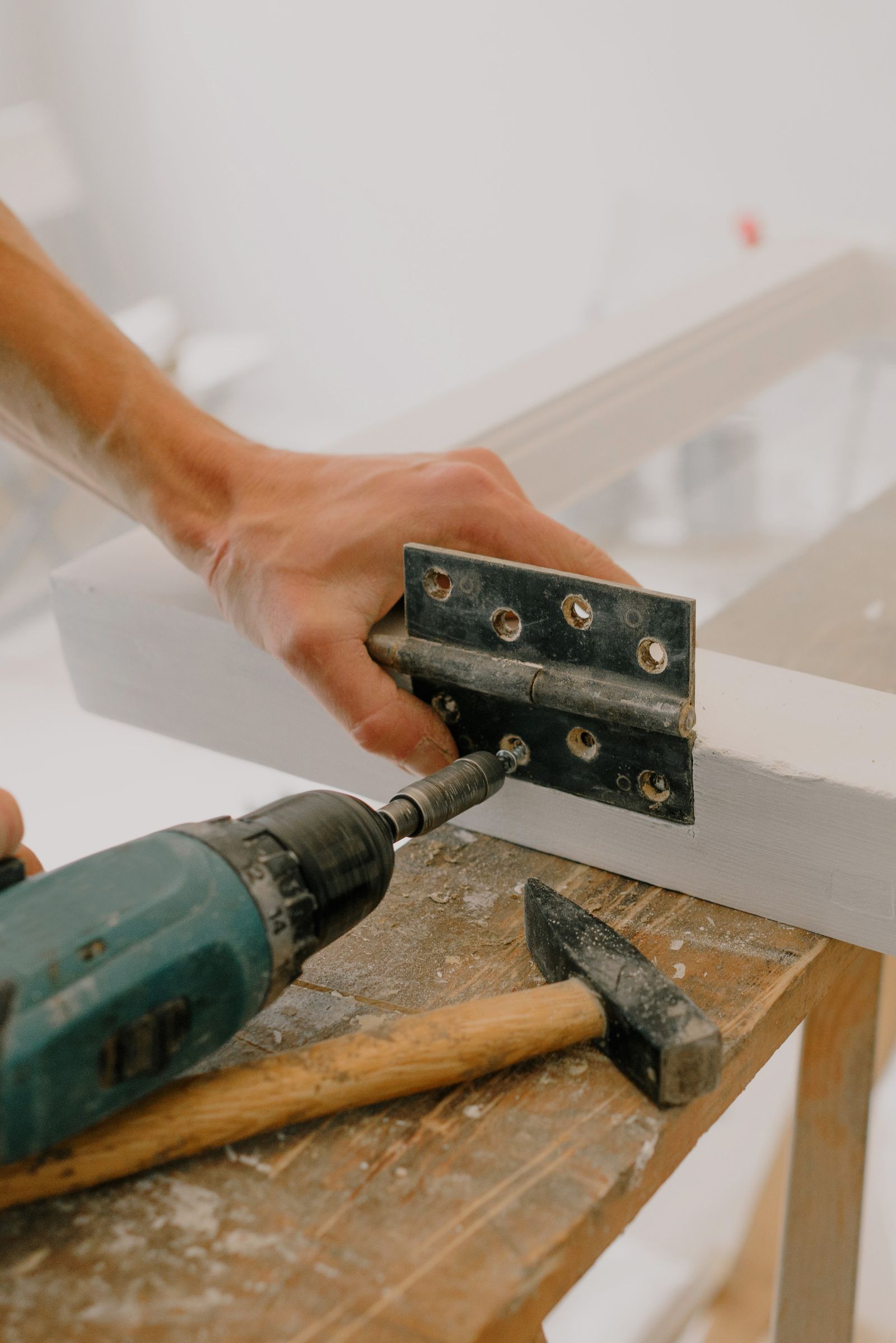 Fire door hinge being fitted by hand with a drill driver