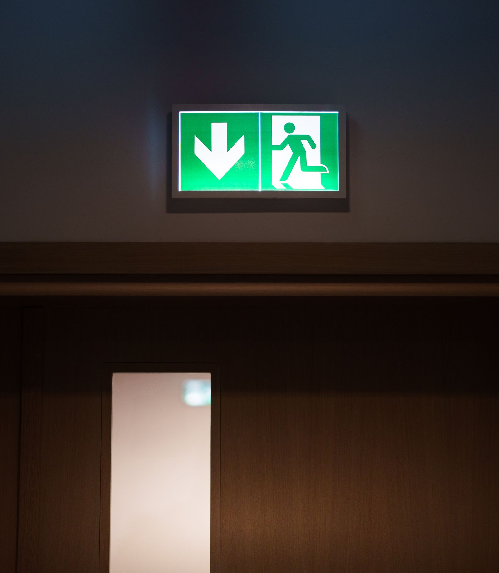 Timber fire door with vision panel below an illuminated fire exit sign